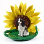 Cavalier King Charles Black/White Figurine Sitting on a Green Leaf in Front of a Yellow Sunflower