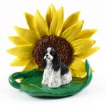 Cocker Spaniel Black/White Figurine Sitting on a Green Leaf in Front of a Yellow Sunflower