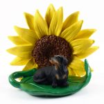 Dachshund Black Figurine Sitting on a Green Leaf in Front of a Yellow Sunflower