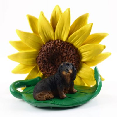 Dachshund Black Long Hair Figurine Sitting on a Green Leaf in Front of a Yellow Sunflower