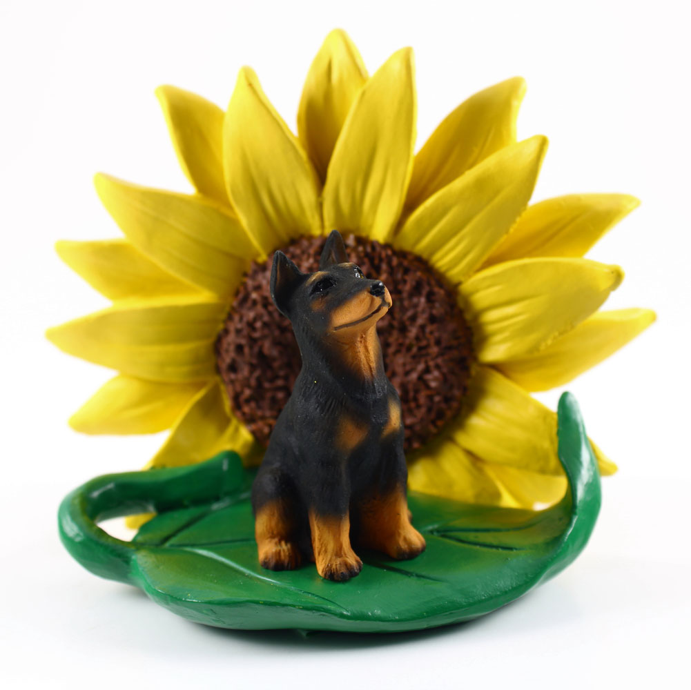 Doberman Pinscher Black Figurine Sitting on a Green Leaf in Front of a Yellow Sunflower