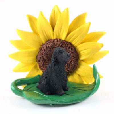 English Cocker Spaniel Black Figurine Sitting on a Green Leaf in Front of a Yellow Sunflower