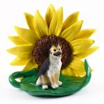 German Shepherd Black/Tan Figurine Sitting on a Green Leaf in Front of a Yellow Sunflower