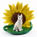 German Shepherd White Figurine Sitting on a Green Leaf in Front of a Yellow Sunflower