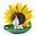 Japanese Chin Black Figurine Sitting on a Green Leaf in Front of a Yellow Sunflower