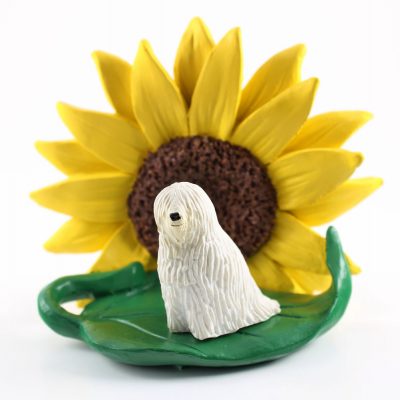 Komondor Figurine Sitting on a Green Leaf in Front of a Yellow Sunflower