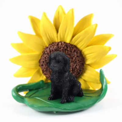 Labradoodle Black Figurine Sitting on a Green Leaf in Front of a Yellow Sunflower
