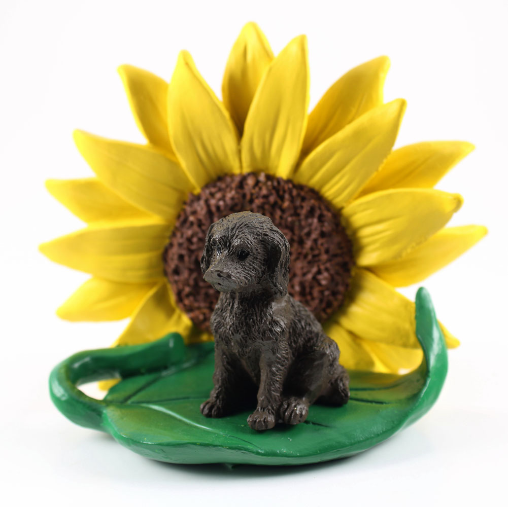 Labradoodle Chocolate Figurine Sitting on a Green Leaf in Front of a Yellow Sunflower