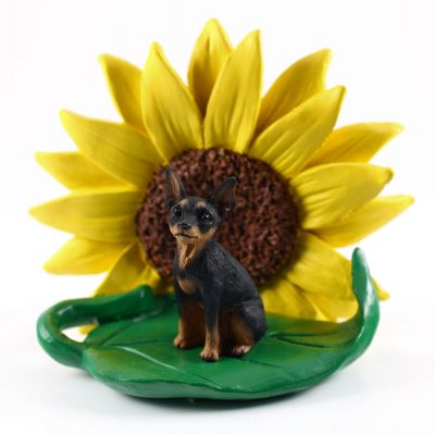 Mini Pinscher Black Figurine Sitting on a Green Leaf in Front of a Yellow Sunflower