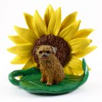 Norfolk Terrier Figurine Sitting on a Green Leaf in Front of a Yellow Sunflower