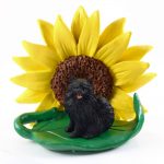 Pomeranian Black Figurine Sitting on a Green Leaf in Front of a Yellow Sunflower