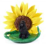 Poodle Black Figurine Sitting on a Green Leaf in Front of a Yellow Sunflower