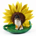 Sheltie Tri Color Figurine Sitting on a Green Leaf in Front of a Yellow Sunflower